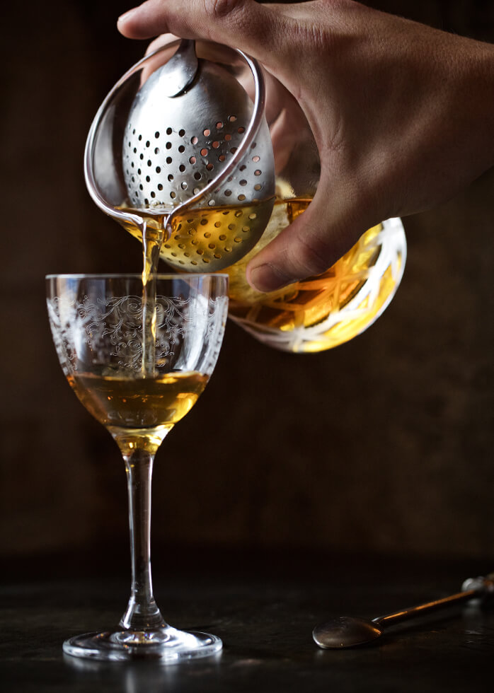 A picture of a cocktail being poured into a glass.