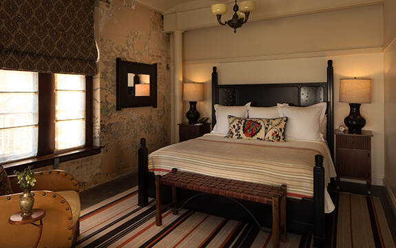 A picture of the bedroom in Hotel Emma's plaza suite option. Pictured is a king sized bed with nightstands and a window.