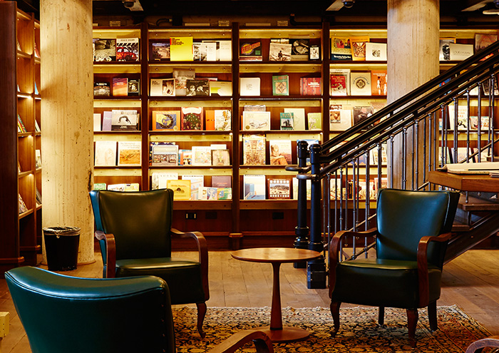 three leather chairs at the base of a staircase, surrounded by books in the hotel emma library